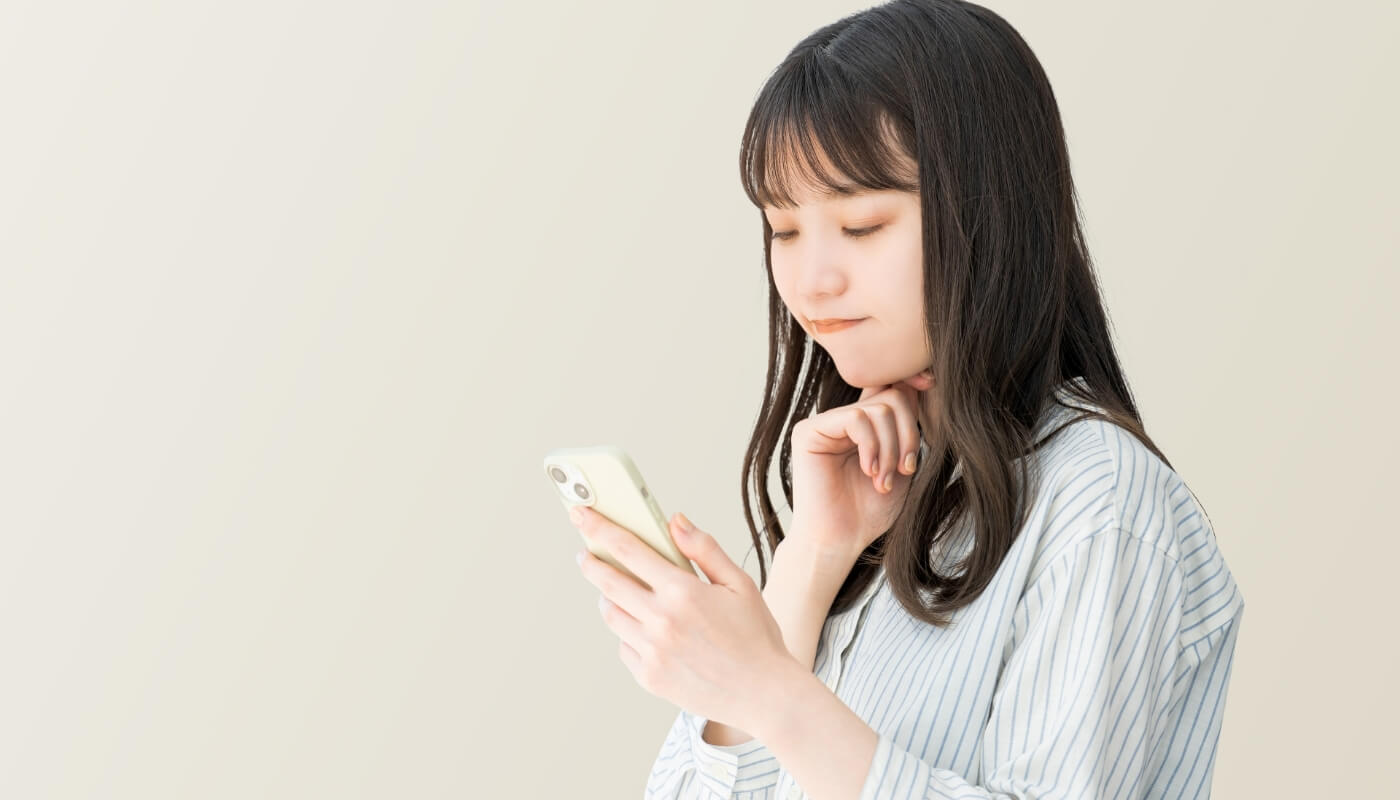 スマホを見て悩む女性