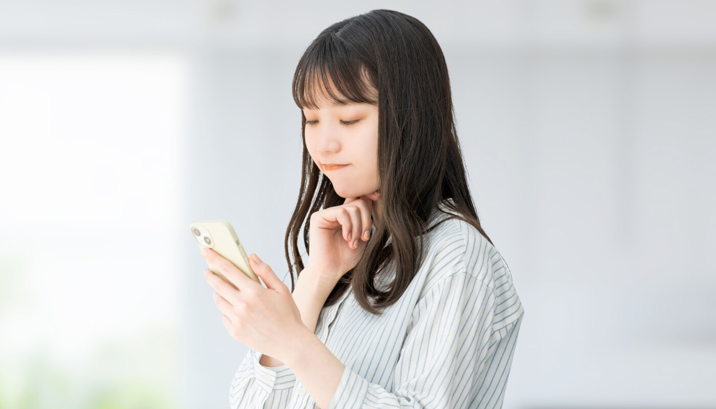 スマホを見て悩む女性